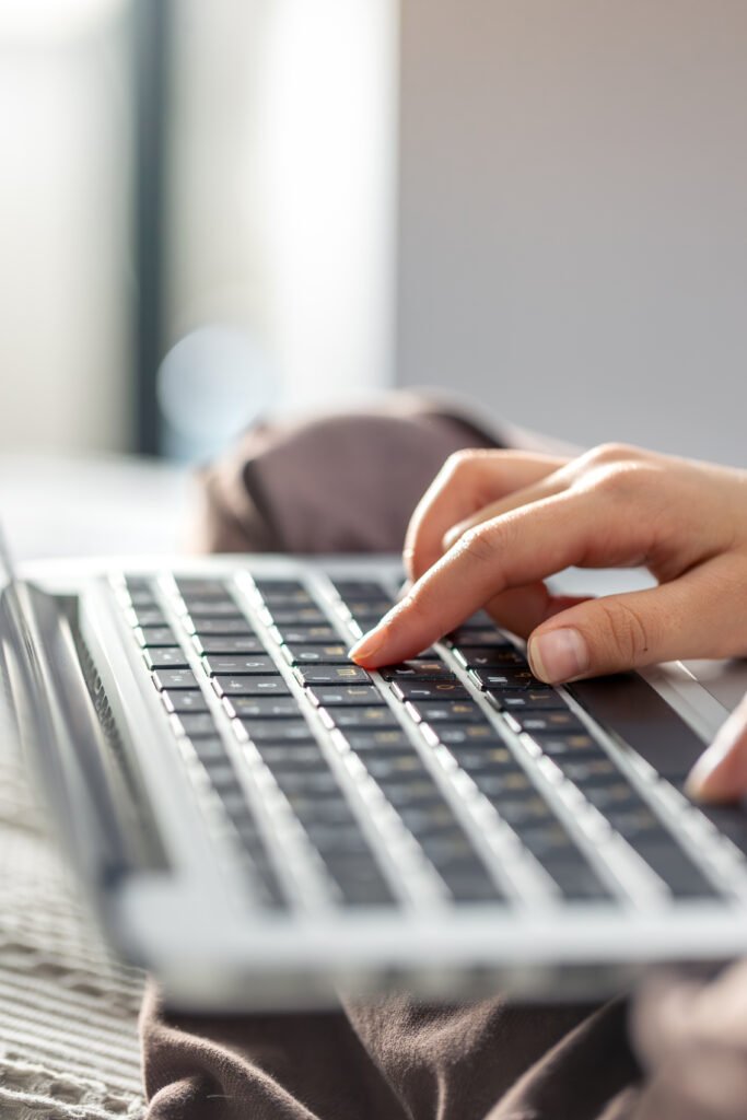 the girl is typing on the laptop keyboard. girl's hands on the keyboard.
